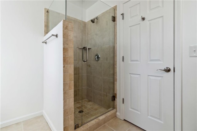 bathroom featuring tile patterned flooring, a shower stall, and baseboards