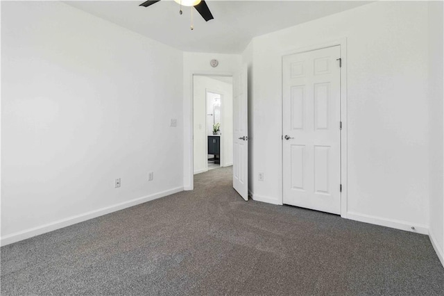 unfurnished bedroom with dark colored carpet, a ceiling fan, and baseboards