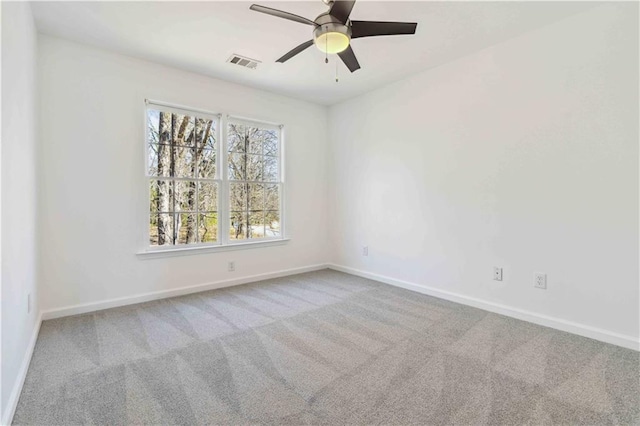 empty room with carpet floors, visible vents, baseboards, and a ceiling fan