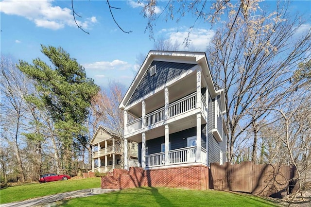 view of front facade with a balcony, fence, and a front lawn