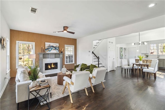 living room with visible vents, dark wood finished floors, a ceiling fan, stairs, and a high end fireplace