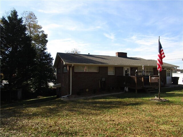 back of property featuring a wooden deck and a yard