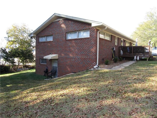 view of home's exterior with a wooden deck and a lawn