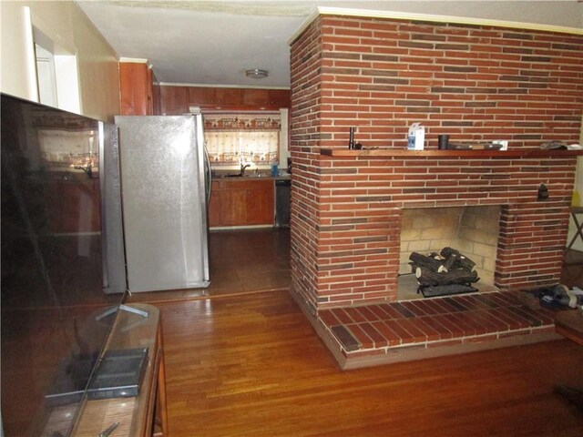 unfurnished living room with sink, dark hardwood / wood-style floors, and a brick fireplace