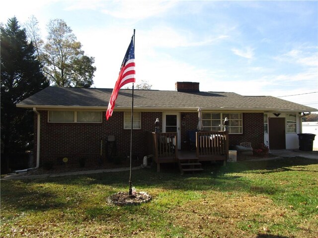 back of property with a deck and a yard