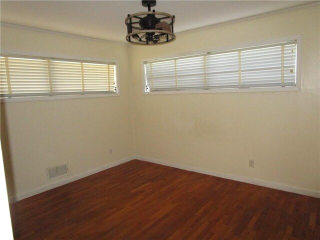 unfurnished room with an inviting chandelier, dark wood-type flooring, and ornamental molding