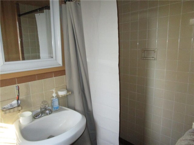 bathroom featuring sink, backsplash, and tile walls