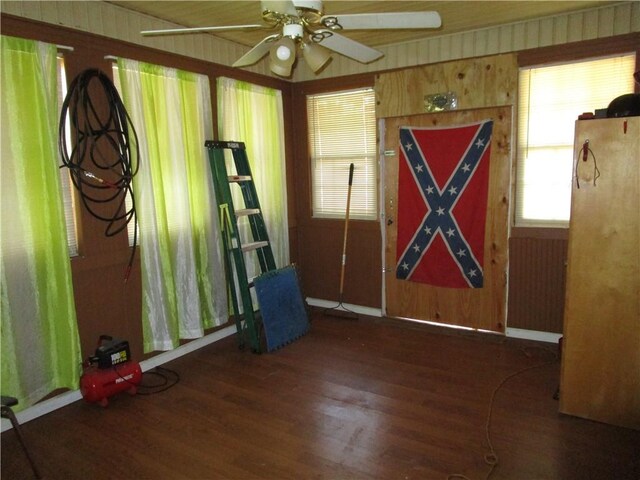 unfurnished room with dark hardwood / wood-style floors, ceiling fan, and wood walls