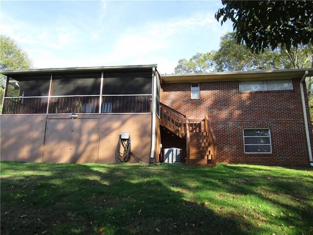 rear view of house with a lawn and a sunroom