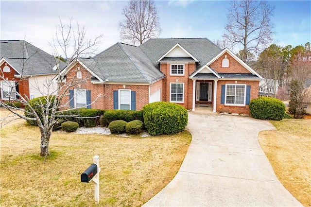 traditional-style house featuring brick siding, concrete driveway, a front lawn, and roof with shingles