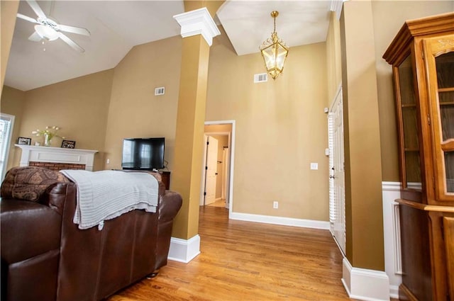 interior space with light wood-type flooring, visible vents, high vaulted ceiling, baseboards, and ornate columns