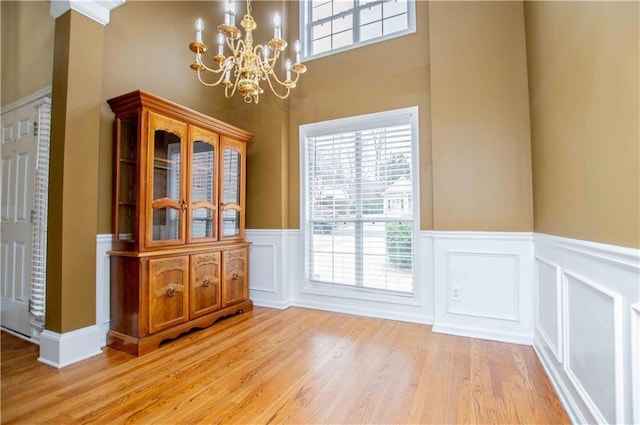 unfurnished dining area featuring a wealth of natural light, light wood-style flooring, and wainscoting