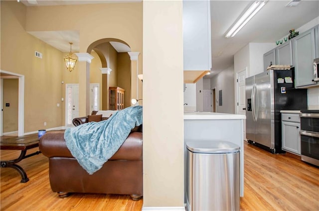 kitchen with visible vents, light wood-type flooring, gray cabinets, arched walkways, and stainless steel appliances