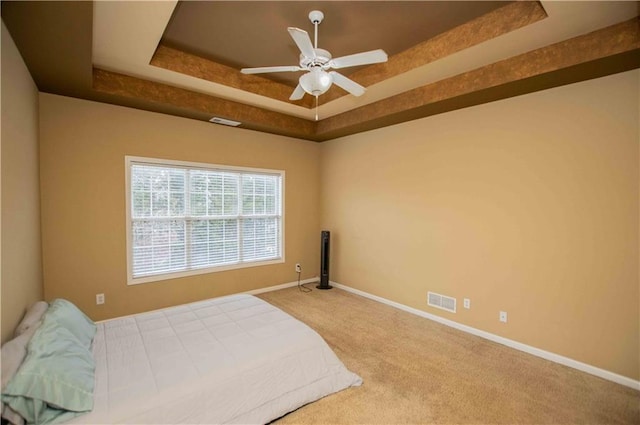 bedroom with a raised ceiling, baseboards, visible vents, and carpet floors