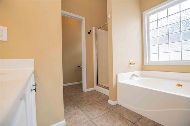 bathroom with tile patterned floors, a garden tub, a stall shower, baseboards, and vanity