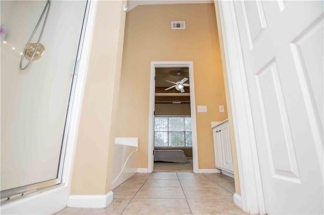 hallway featuring light tile patterned floors, visible vents, and baseboards