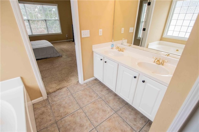 ensuite bathroom featuring a sink, a healthy amount of sunlight, and tile patterned flooring