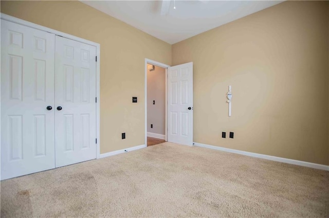 unfurnished bedroom featuring a closet, carpet flooring, a ceiling fan, and baseboards