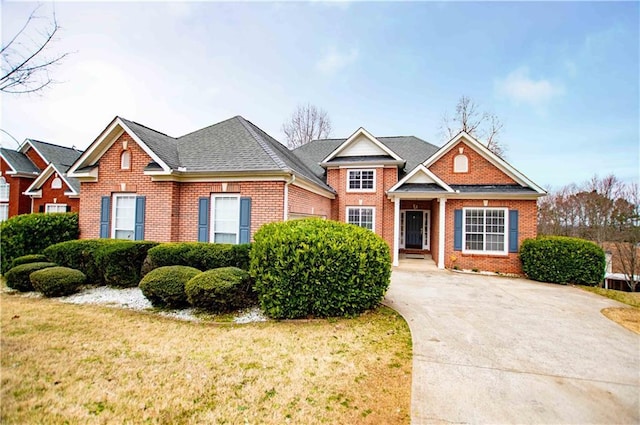 view of front of home with brick siding, a shingled roof, and a front yard