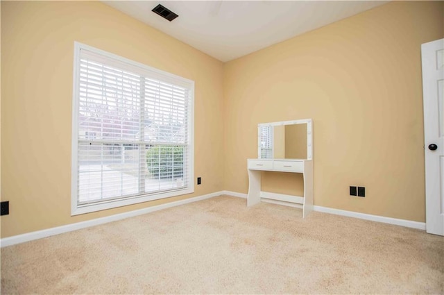 empty room with carpet, visible vents, and baseboards