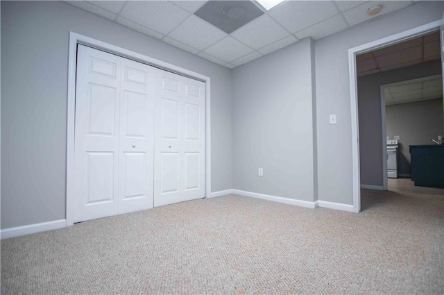 unfurnished bedroom featuring a drop ceiling, baseboards, and carpet flooring