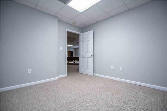 carpeted empty room with a paneled ceiling and baseboards