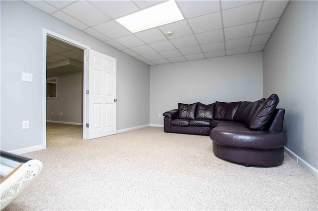 carpeted living area featuring a paneled ceiling and baseboards