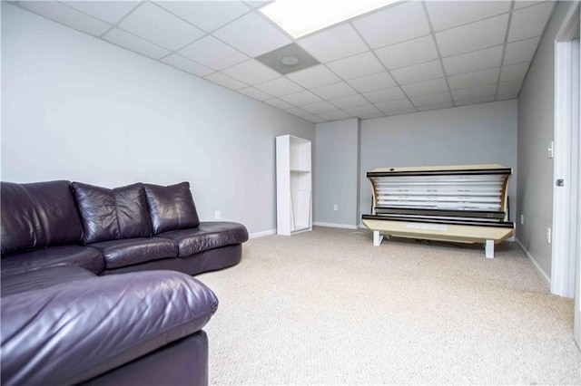 carpeted living area featuring baseboards and a drop ceiling