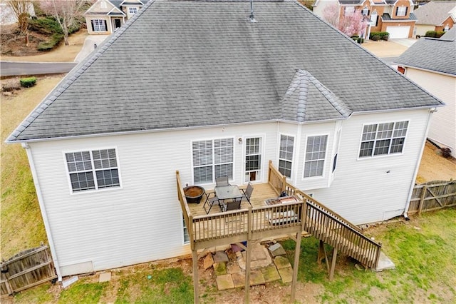 back of property with roof with shingles, a deck, and fence