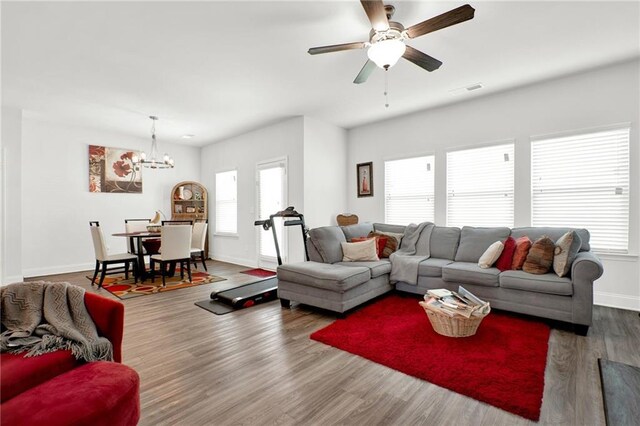 living room featuring a chandelier, baseboards, wood finished floors, and ceiling fan