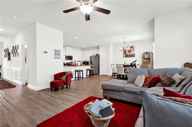 living area with wood finished floors, a ceiling fan, a chandelier, and recessed lighting