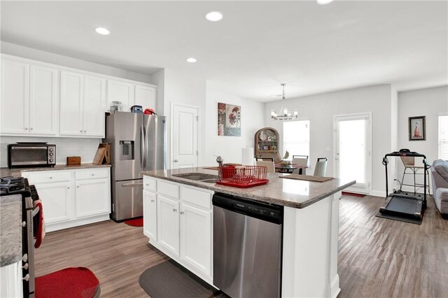 kitchen with appliances with stainless steel finishes, a sink, wood finished floors, white cabinets, and recessed lighting