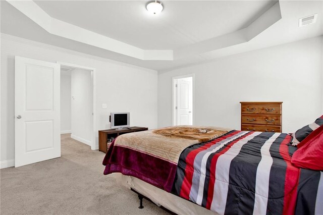 bedroom featuring a tray ceiling, carpet floors, and baseboards