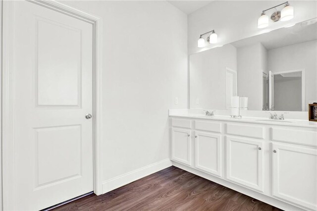bathroom featuring wood finished floors, double vanity, and baseboards