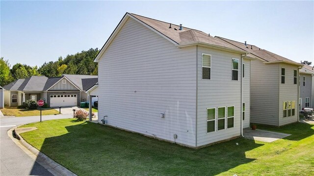 view of side of home featuring a yard, an attached garage, and driveway