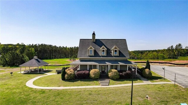 view of front of property featuring a gazebo, a view of trees, a front yard, and a porch