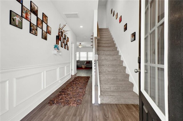 stairs featuring a ceiling fan, wood finished floors, a wainscoted wall, and recessed lighting