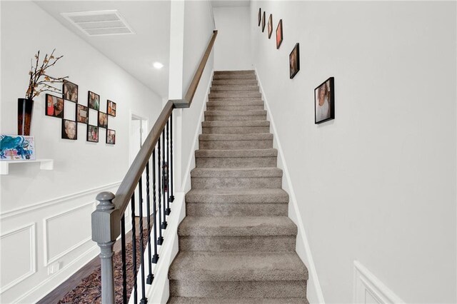 stairway featuring a wainscoted wall, recessed lighting, wood finished floors, and a decorative wall