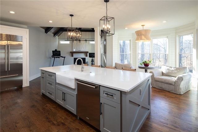 kitchen with open floor plan, light countertops, appliances with stainless steel finishes, and a center island with sink