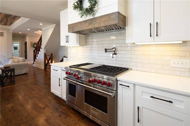 kitchen with light countertops, range with two ovens, custom exhaust hood, and white cabinetry