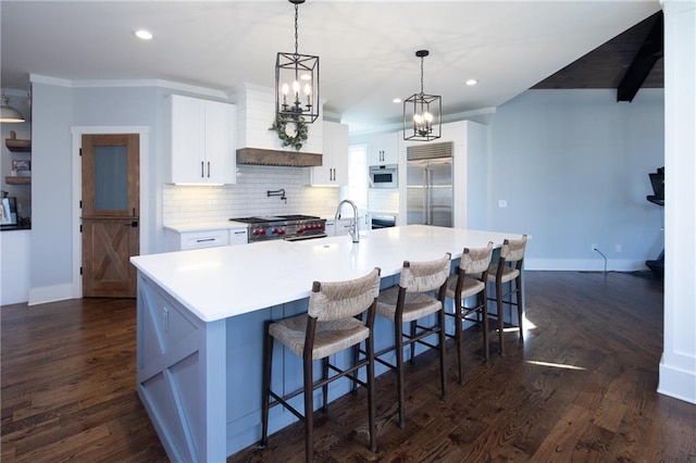 kitchen featuring white cabinets, high end appliances, a spacious island, decorative light fixtures, and light countertops