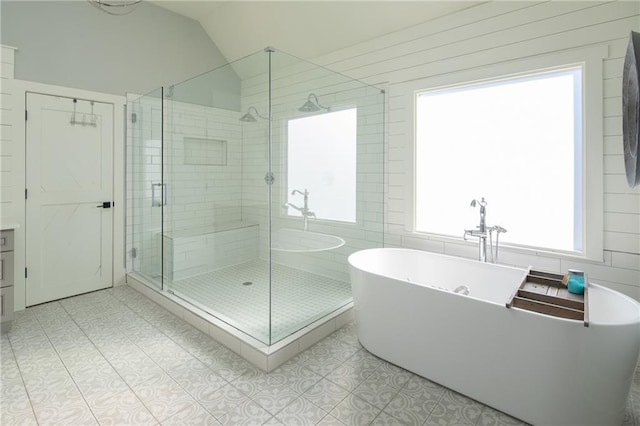 bathroom with a stall shower, tile patterned flooring, a freestanding tub, and lofted ceiling