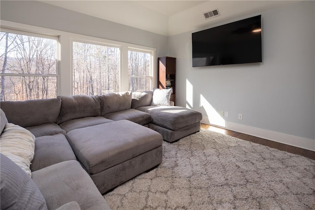 living area featuring visible vents, baseboards, and wood finished floors