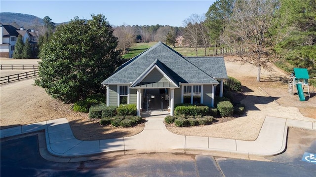 view of front of property featuring a mountain view, a playground, fence, and roof with shingles