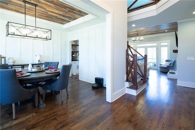 dining room featuring baseboards, dark wood finished floors, a raised ceiling, an inviting chandelier, and crown molding