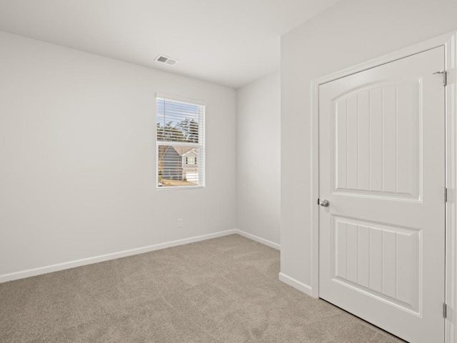 empty room featuring light carpet, visible vents, and baseboards