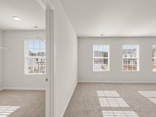 carpeted empty room with visible vents and baseboards