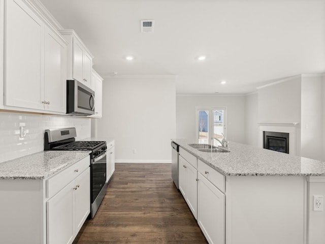 kitchen featuring dark wood finished floors, backsplash, appliances with stainless steel finishes, a kitchen island with sink, and a sink