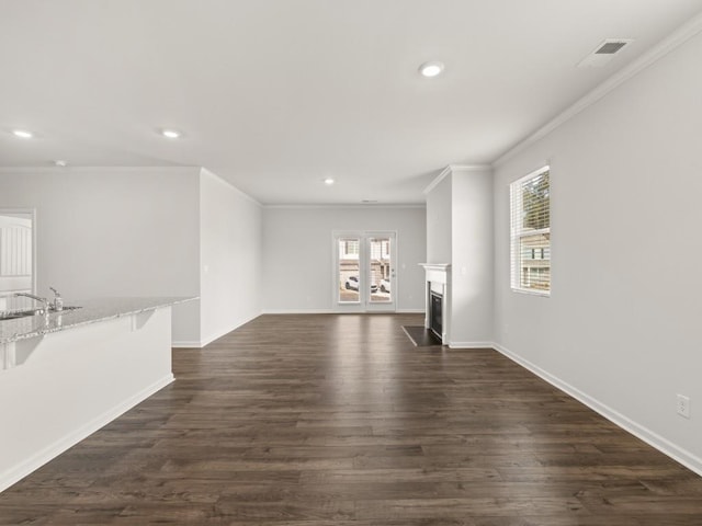 unfurnished living room with a healthy amount of sunlight, dark wood-style floors, a fireplace with flush hearth, and visible vents