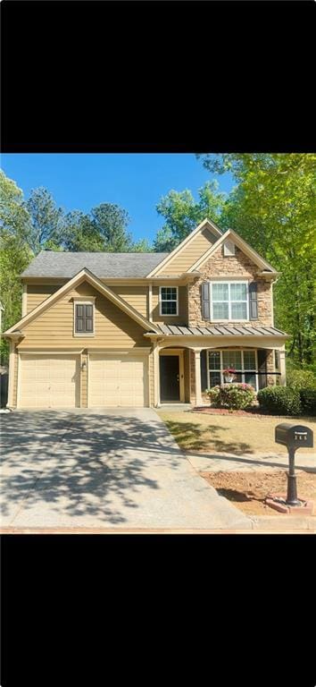 view of front of property with concrete driveway, an attached garage, and a standing seam roof